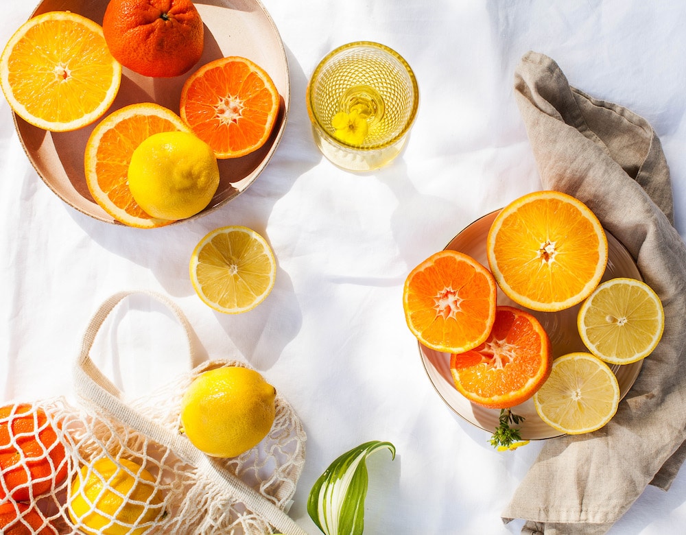 vitamine C juicy citrus fruits whole and cut on the tablecloth in the sun. Lemons and oranges. Healthy diet. Vitamins. Copy space.
