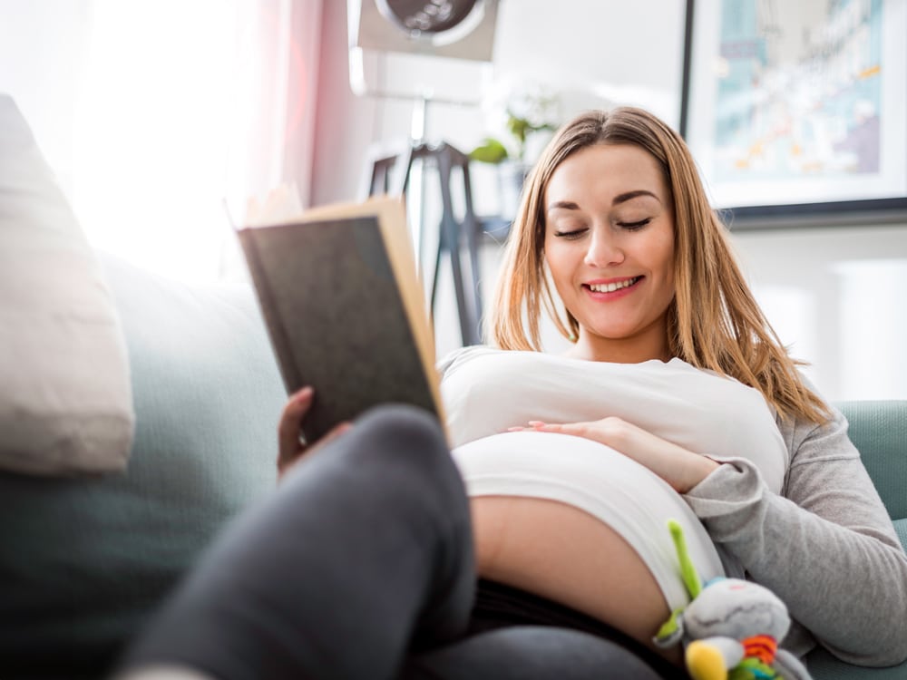 zwangere vrouw ontspannend op de bank leesboek