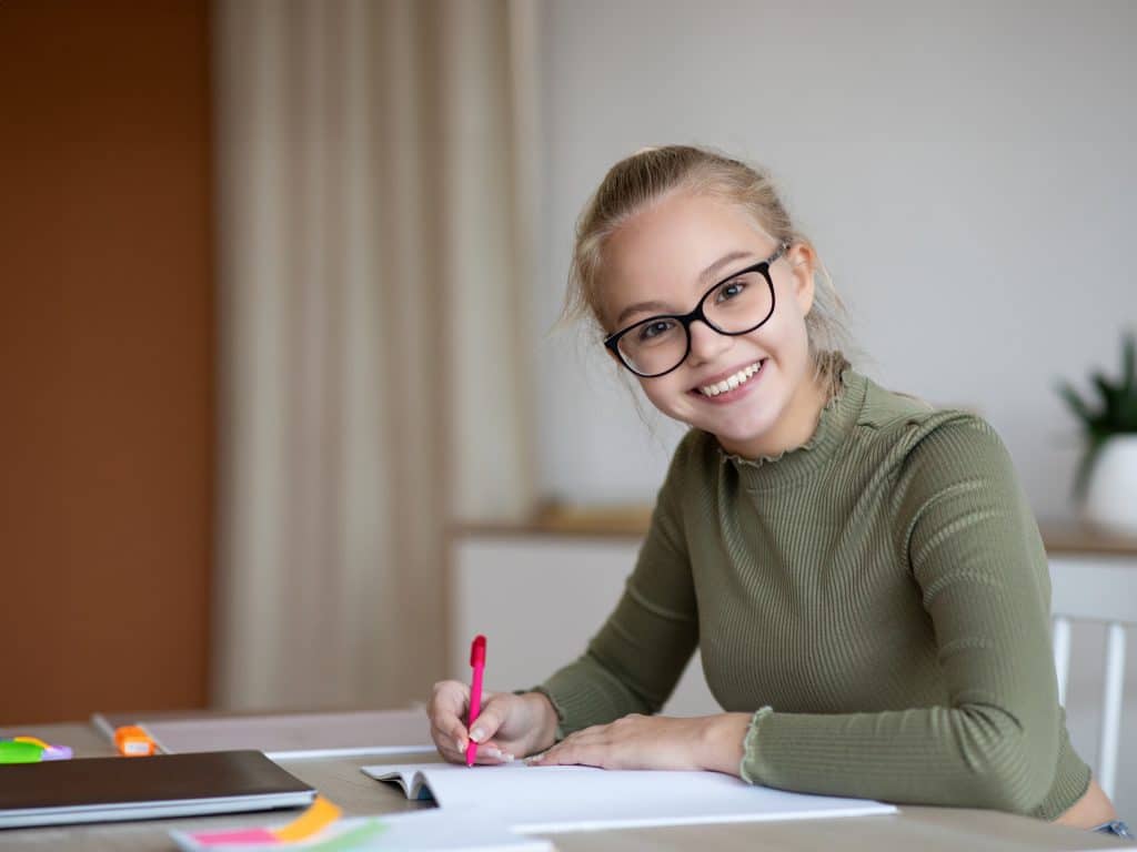 mooi schoolmeisje schrijft in notitieblok en lacht