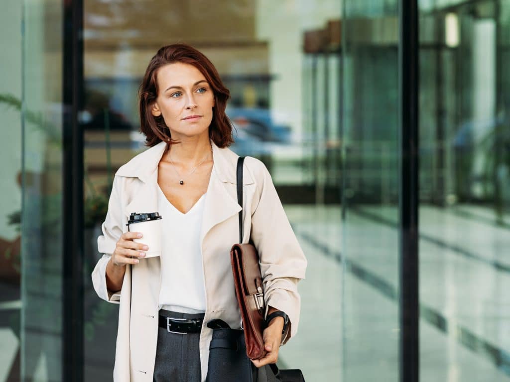 zakenvrouw van middelbare leeftijd die koffie vasthoudt uitgaan naar werk
