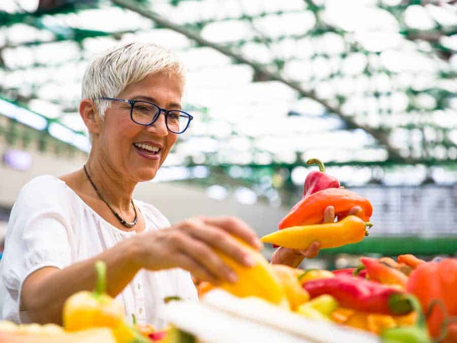 knappe vrouw die een bril draagt koopt groente