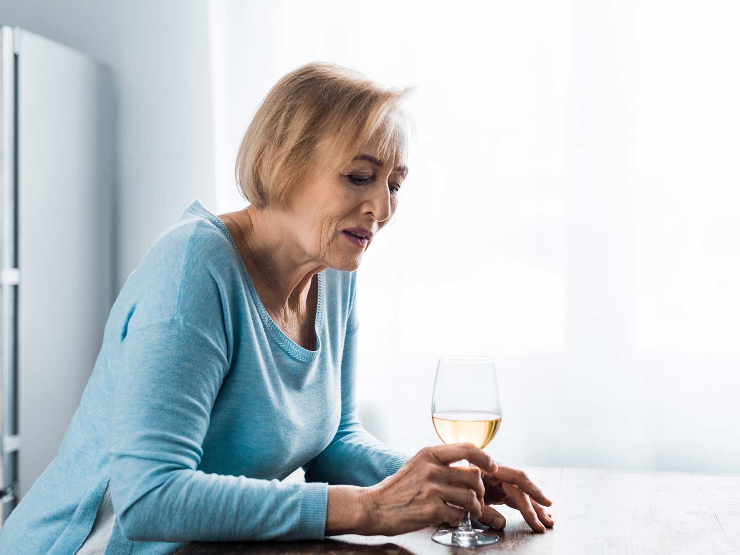 lonely senior woman in casual clothes holding wine