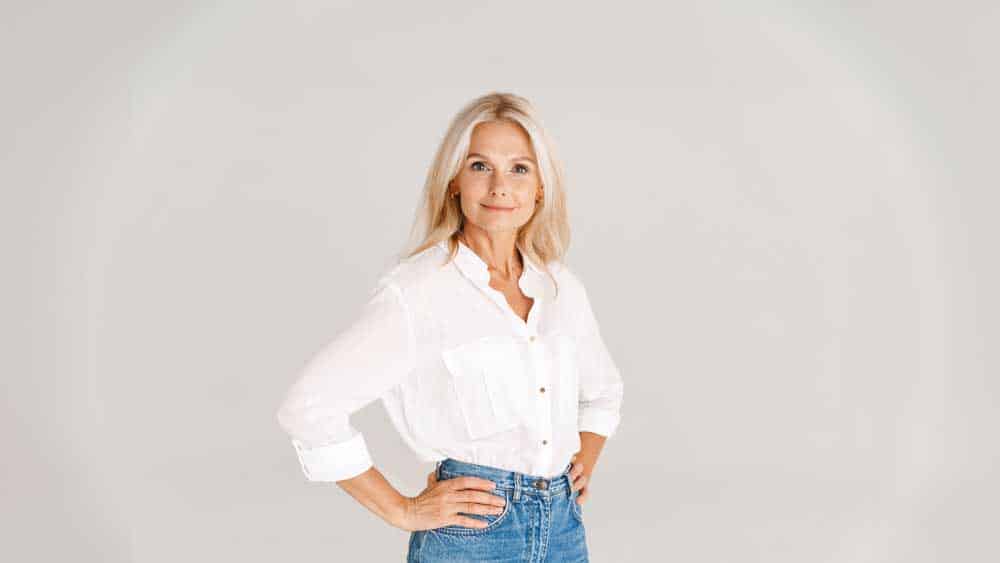 volwassen blonde vrouw in shirt die lacht en naar de camera kijkt
