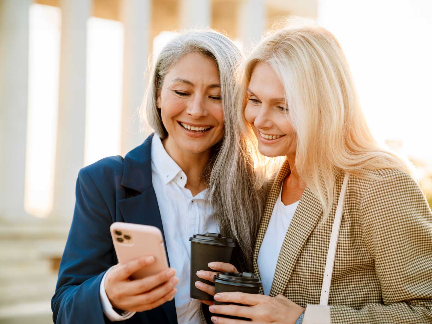 volwassen vrouwen gebruiken mobiele telefoon en delen met vrienden en drinken koffie