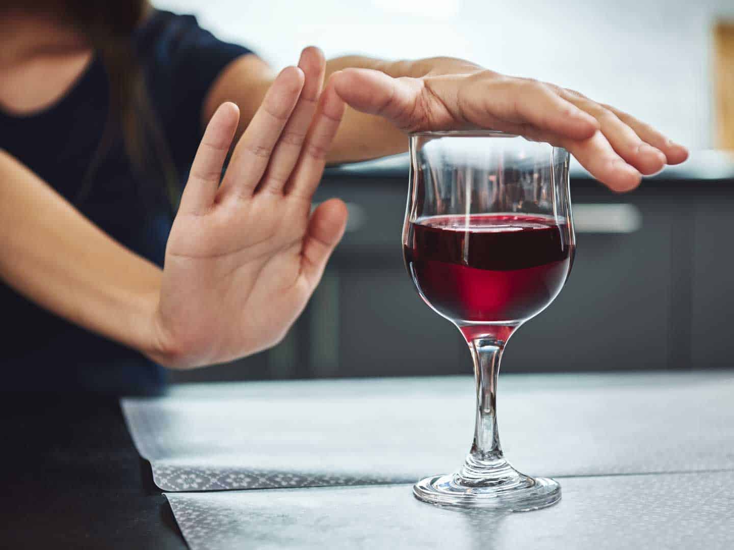 woman with glass of wine stopping